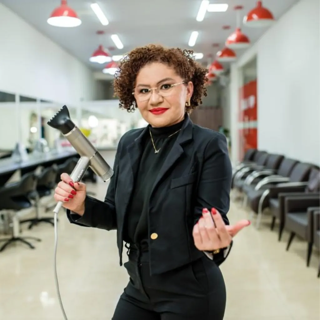 Irailde Cardoso no salão, segurando um secador de cabelo