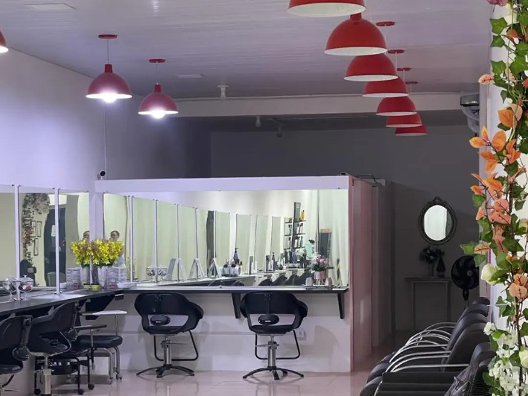 Área de atendimento do salão, com cadeiras, espelhos e flores